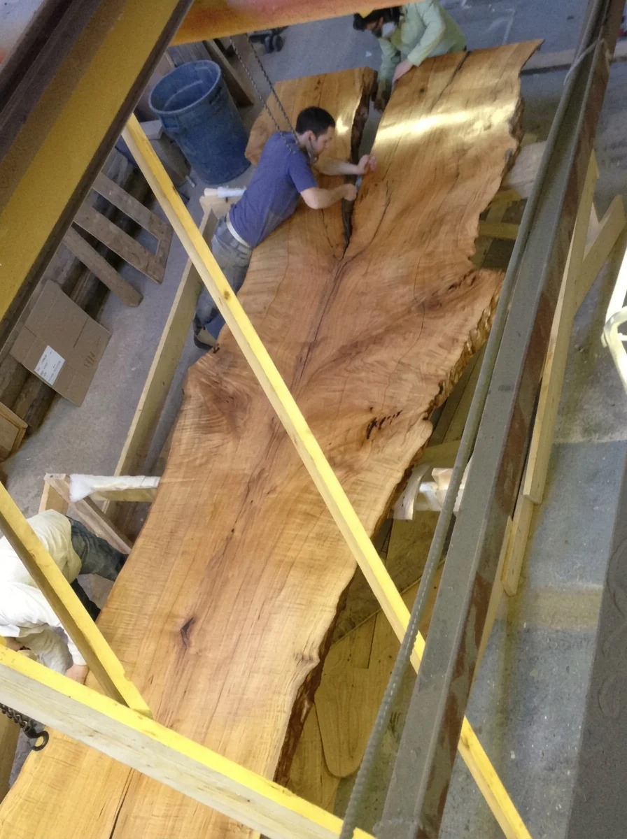 Massive live-edge hard maple slab being rigged and positioned in the workshop for the One Ocean sales centre, Miami Beach — interiors by Yabu Pushelberg