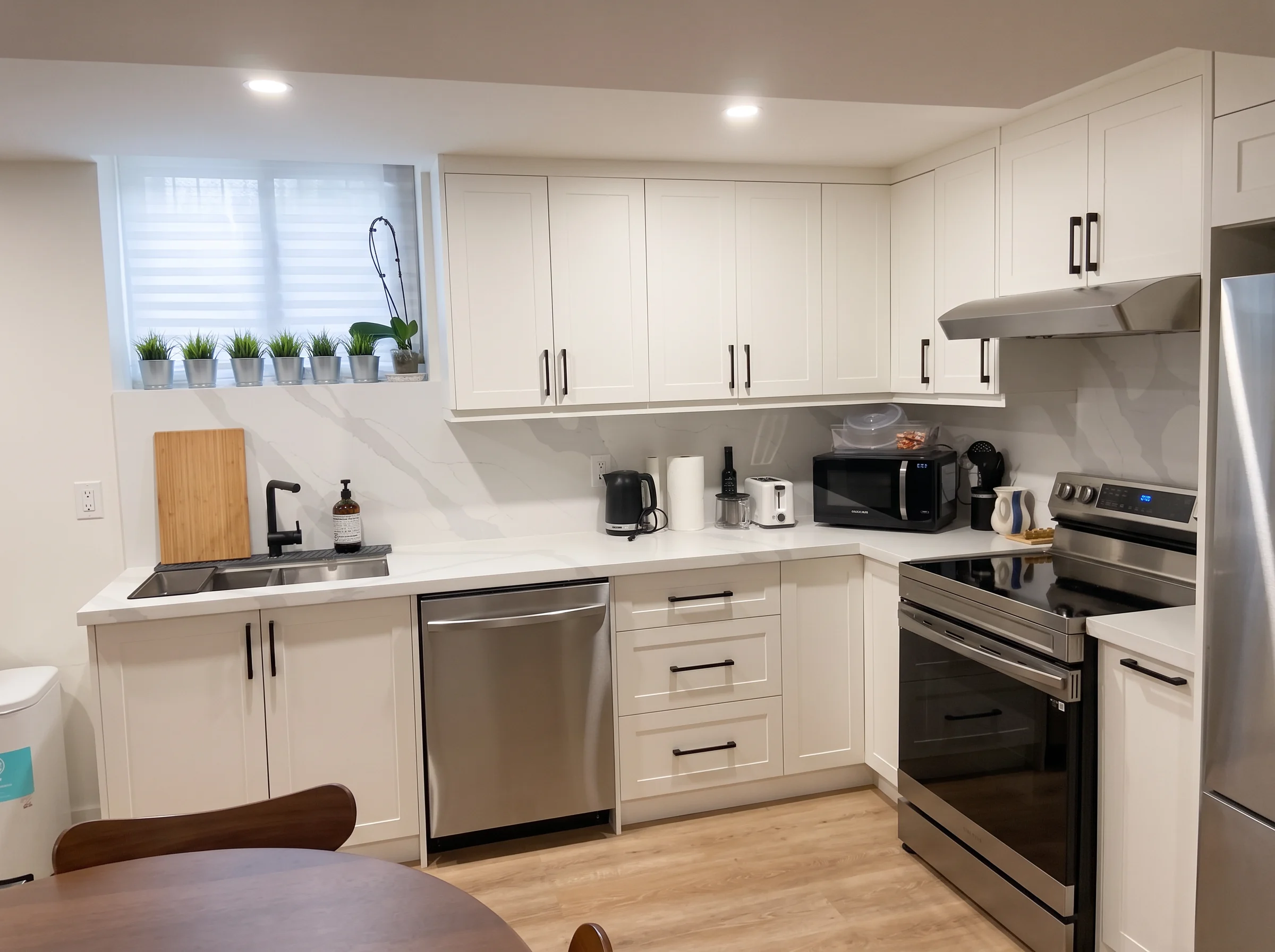 White shaker kitchen — full L-shaped run with quartz counters, matching stone backsplash, stainless appliances and matte black hardware